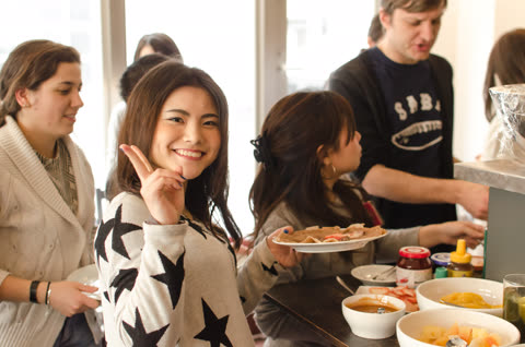 Woman makes peace sign, holding plate of food in cafe.