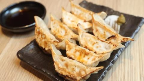 Fried dumplings arranged on a dark plate.