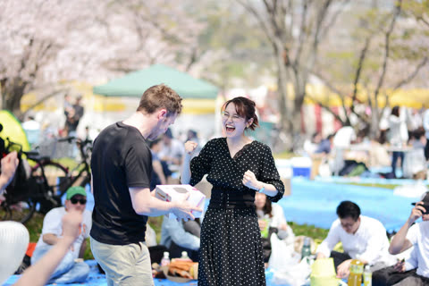 Woman receives a box, joyfully celebrating outdoors.