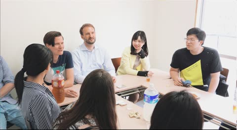 Group of people sitting around a table, talking.