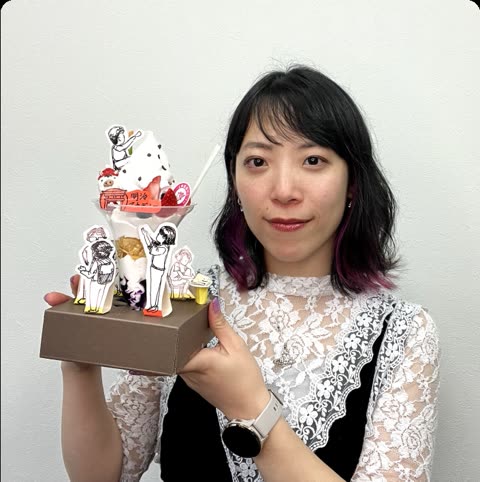 Woman holds elaborate dessert featuring illustrated figures.